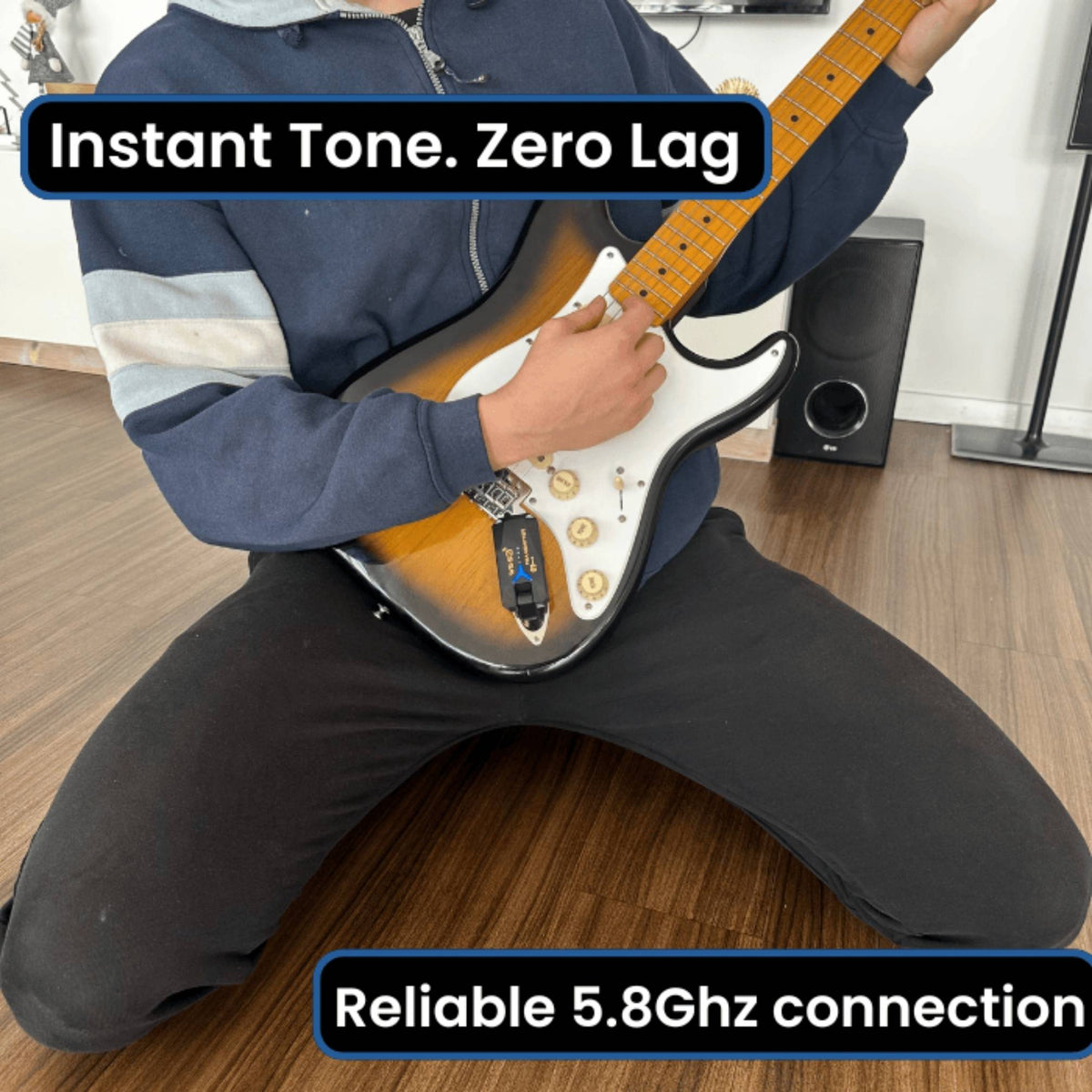 A person sitting on a wooden floor holds an electric guitar with a sunburst finish and white pickguard. The image includes text overlays reading 'Instant Tone.