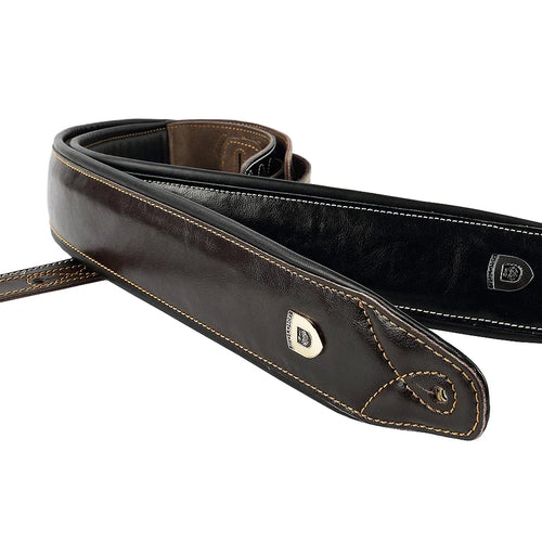 A dark brown leather guitar strap with light tan contrast stitching and a silver metal shield logo, shown on a plain white background.